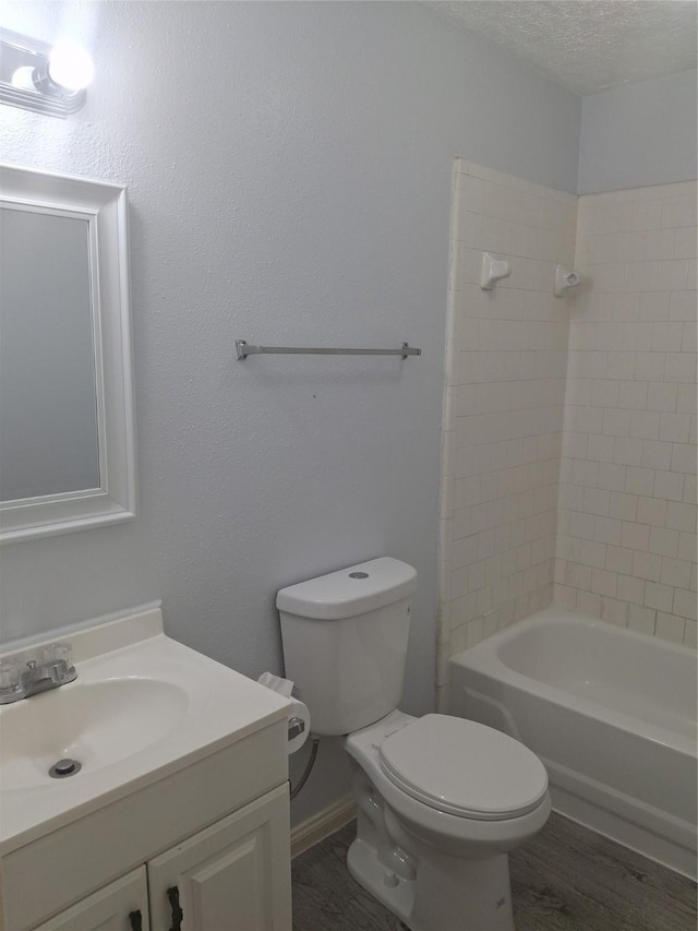 bathroom with a textured ceiling, toilet, shower / bathing tub combination, wood finished floors, and vanity