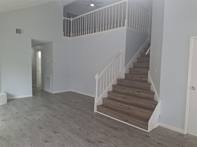 stairs with baseboards, wood finished floors, a towering ceiling, and ceiling fan