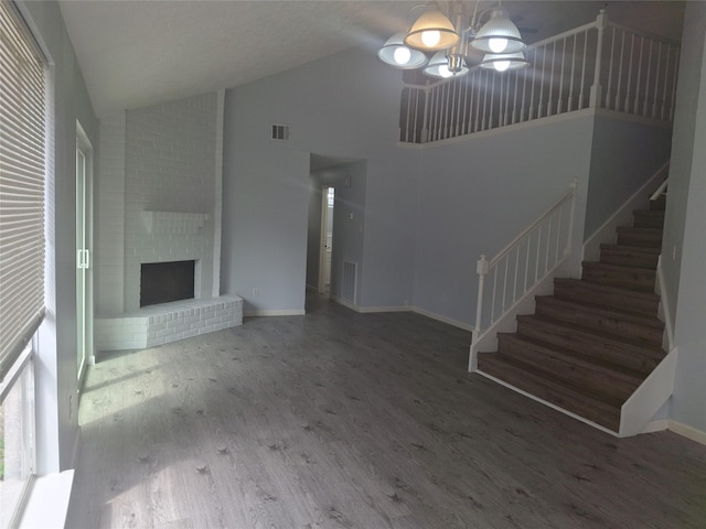 unfurnished living room with high vaulted ceiling, stairs, wood finished floors, baseboards, and visible vents