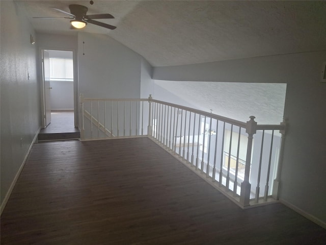 corridor with vaulted ceiling, an upstairs landing, wood finished floors, a textured ceiling, and baseboards