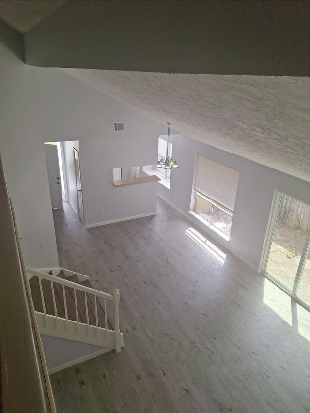 interior space with vaulted ceiling, wood finished floors, visible vents, and baseboards