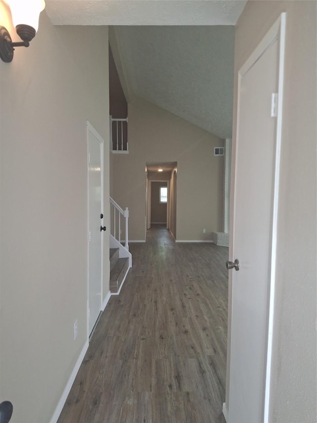 corridor with lofted ceiling, stairway, wood finished floors, visible vents, and baseboards