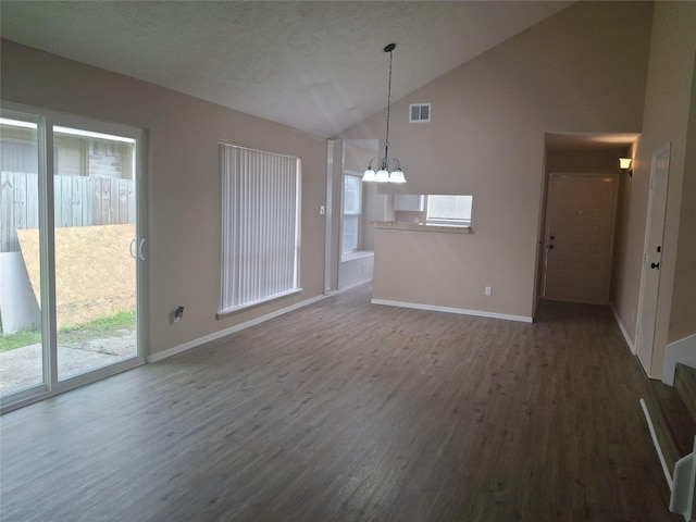 unfurnished living room with vaulted ceiling, an inviting chandelier, baseboards, dark wood-type flooring, and visible vents