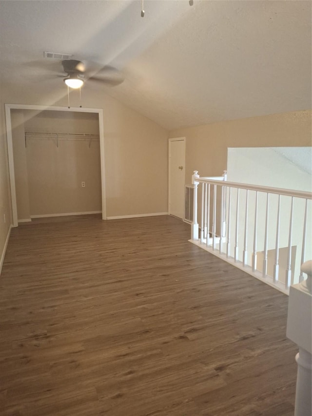 additional living space with dark wood finished floors, ceiling fan, vaulted ceiling, and baseboards