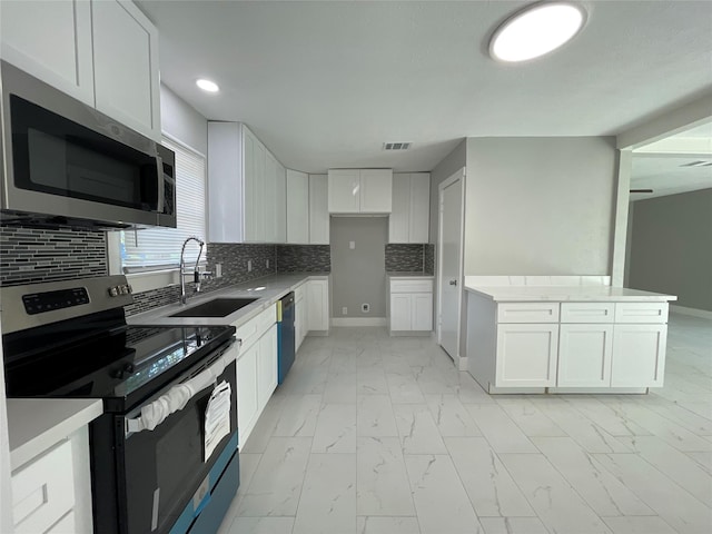 kitchen featuring decorative backsplash, stainless steel appliances, white cabinetry, and sink