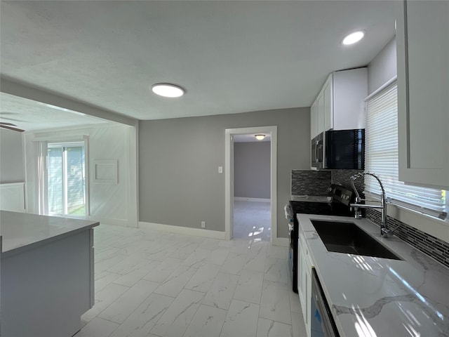 kitchen featuring sink, stainless steel appliances, white cabinetry, and light stone counters