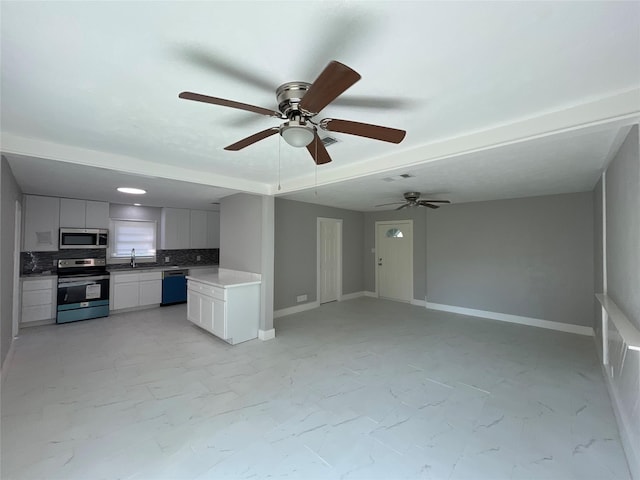 unfurnished living room featuring ceiling fan and sink