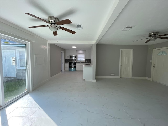 unfurnished living room featuring ceiling fan and sink