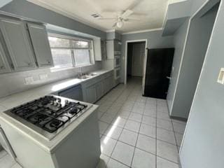 kitchen featuring gray cabinets, stainless steel gas cooktop, crown molding, and sink