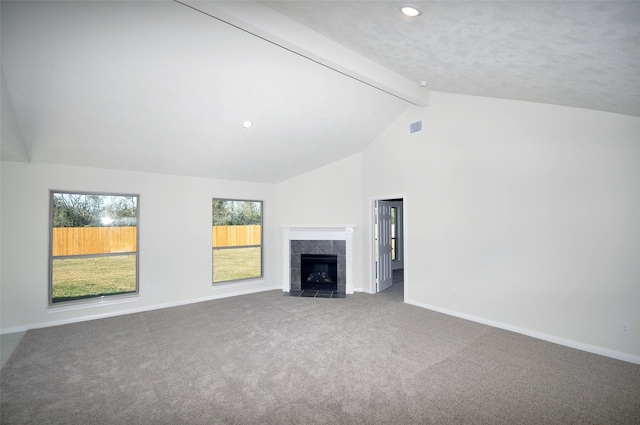 unfurnished living room featuring vaulted ceiling with beams, carpet floors, a textured ceiling, and a tiled fireplace