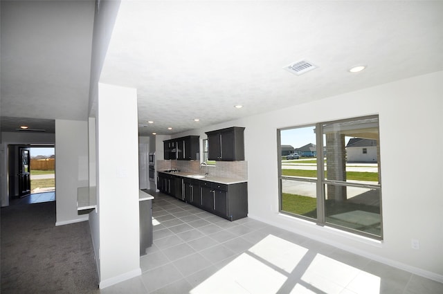 kitchen with sink, light tile patterned floors, backsplash, and a wealth of natural light