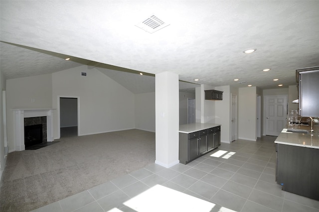 interior space with light carpet, a tiled fireplace, vaulted ceiling, and sink