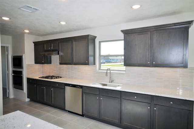 kitchen with sink, decorative backsplash, light stone countertops, light tile patterned floors, and stainless steel appliances