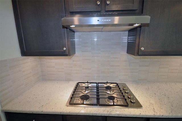 kitchen featuring backsplash, light stone countertops, extractor fan, and stainless steel gas cooktop