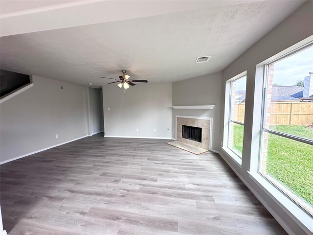 unfurnished living room featuring a tile fireplace, light hardwood / wood-style flooring, and a wealth of natural light