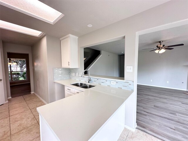 kitchen featuring light tile patterned floors, ceiling fan, sink, white cabinetry, and tasteful backsplash