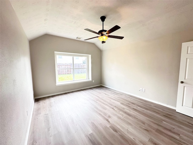 empty room with ceiling fan, hardwood / wood-style floors, lofted ceiling, and a textured ceiling