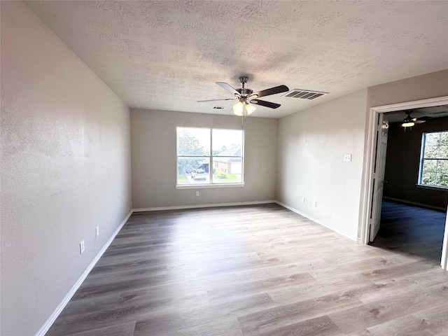 spare room featuring light wood-type flooring, ceiling fan, and a textured ceiling