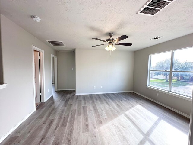 empty room featuring ceiling fan, light hardwood / wood-style flooring, and a textured ceiling