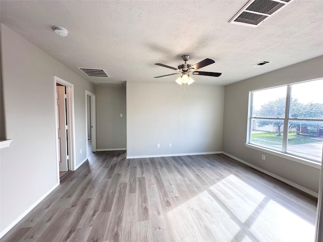 spare room featuring ceiling fan, light hardwood / wood-style floors, and a textured ceiling