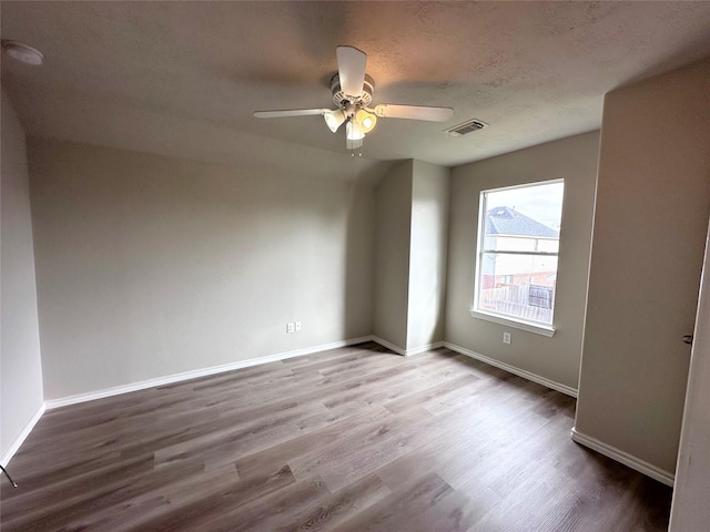 spare room with ceiling fan, light hardwood / wood-style flooring, and a textured ceiling