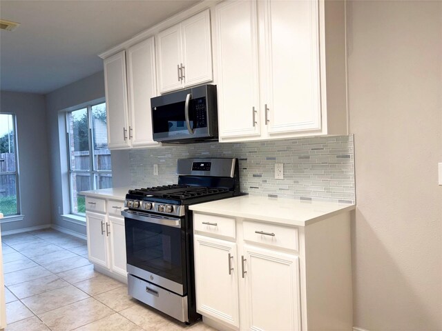 kitchen with a healthy amount of sunlight, stainless steel appliances, white cabinetry, and tasteful backsplash