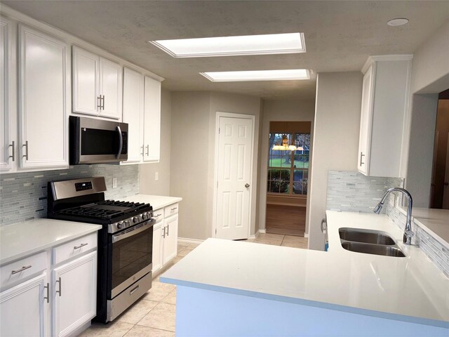 kitchen featuring sink, white cabinets, light tile patterned floors, decorative backsplash, and appliances with stainless steel finishes