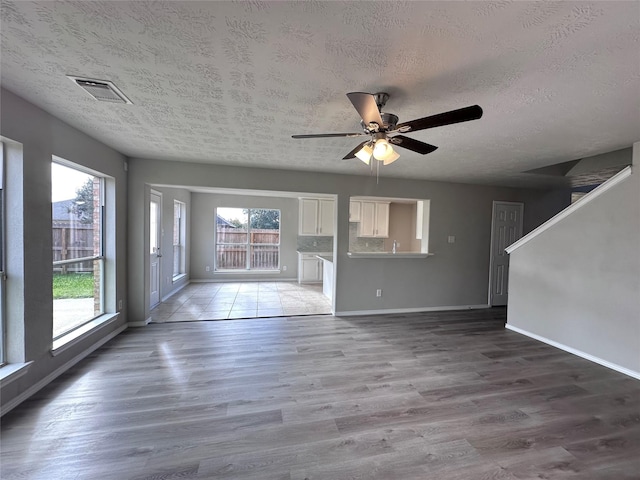 unfurnished living room featuring a healthy amount of sunlight, ceiling fan, and wood-type flooring