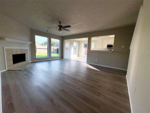 unfurnished living room featuring a fireplace, ceiling fan, and dark hardwood / wood-style flooring