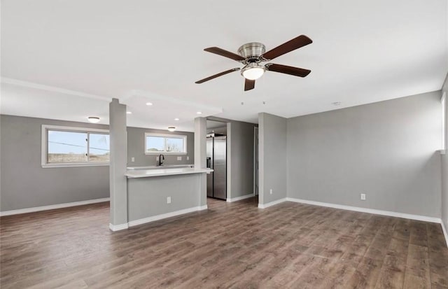 unfurnished living room with dark hardwood / wood-style flooring, ceiling fan, and sink