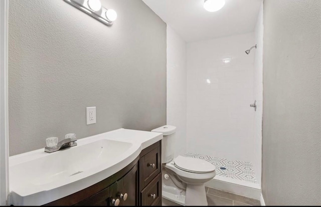 bathroom with tiled shower, vanity, and toilet