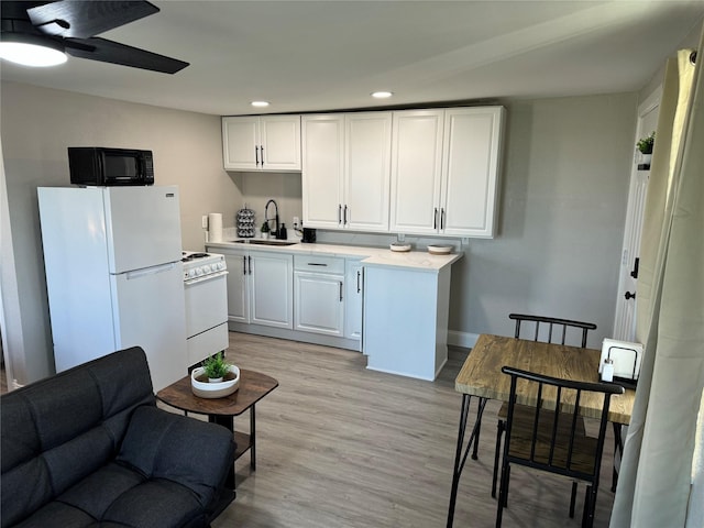 kitchen with light wood-type flooring, white appliances, ceiling fan, sink, and white cabinets