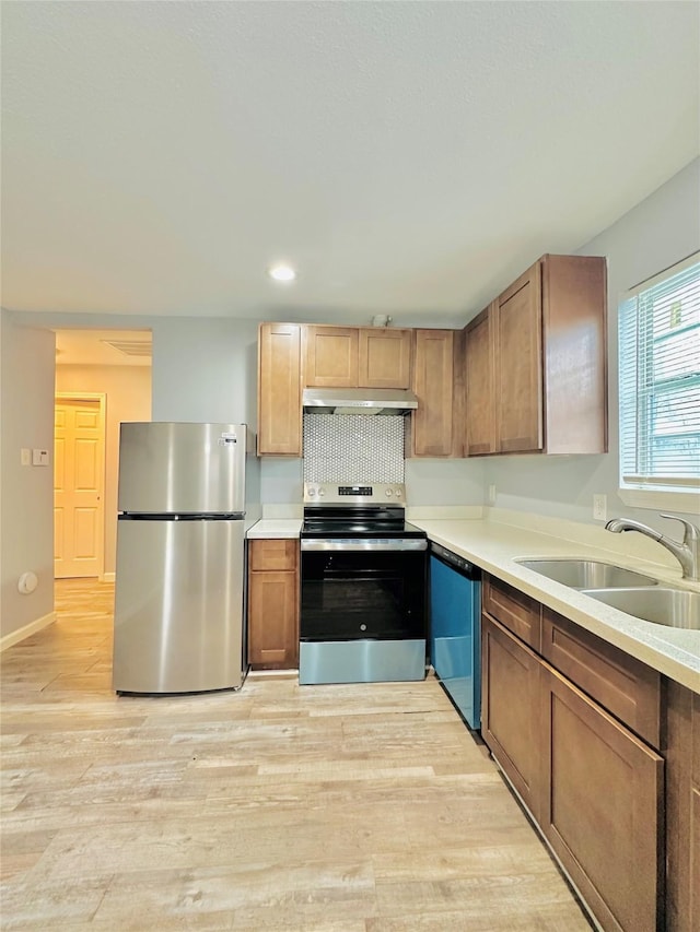 kitchen with sink, stainless steel appliances, light hardwood / wood-style floors, and tasteful backsplash