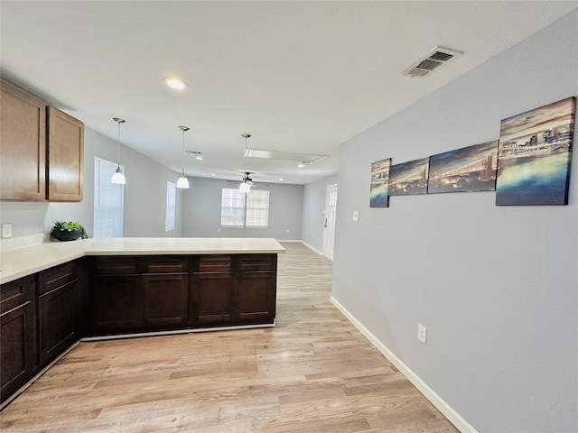 kitchen with kitchen peninsula, decorative light fixtures, light hardwood / wood-style floors, ceiling fan, and dark brown cabinetry