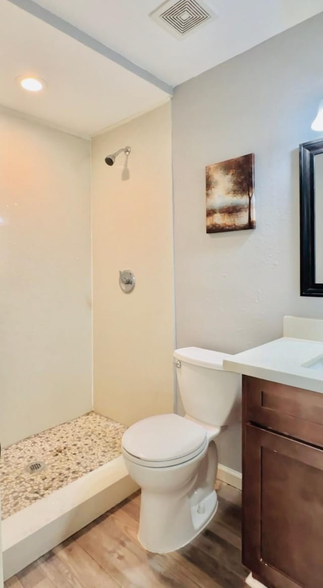 bathroom with wood-type flooring, a shower, vanity, and toilet