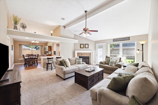 living room with vaulted ceiling with beams, ceiling fan, light wood-type flooring, a textured ceiling, and a tiled fireplace