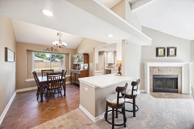 kitchen featuring hanging light fixtures, a kitchen breakfast bar, lofted ceiling with beams, kitchen peninsula, and a fireplace