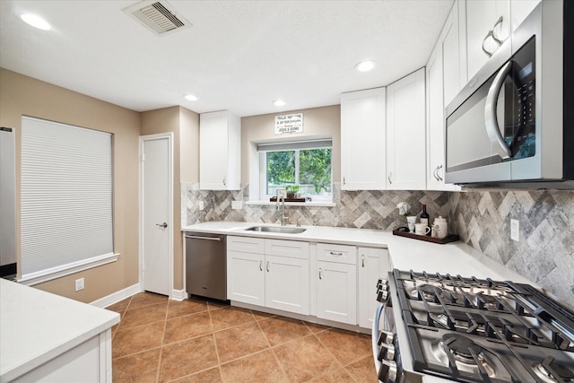 kitchen with white cabinets, appliances with stainless steel finishes, backsplash, and sink