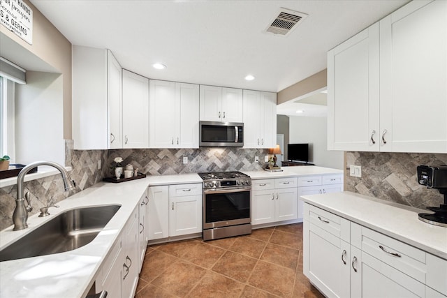 kitchen featuring white cabinets, decorative backsplash, stainless steel appliances, and sink