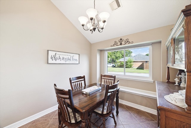 dining room featuring a chandelier, dark tile patterned floors, and lofted ceiling