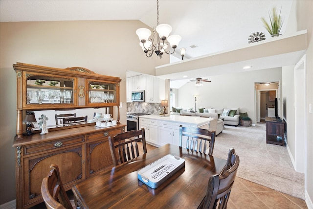 tiled dining room featuring high vaulted ceiling and ceiling fan with notable chandelier