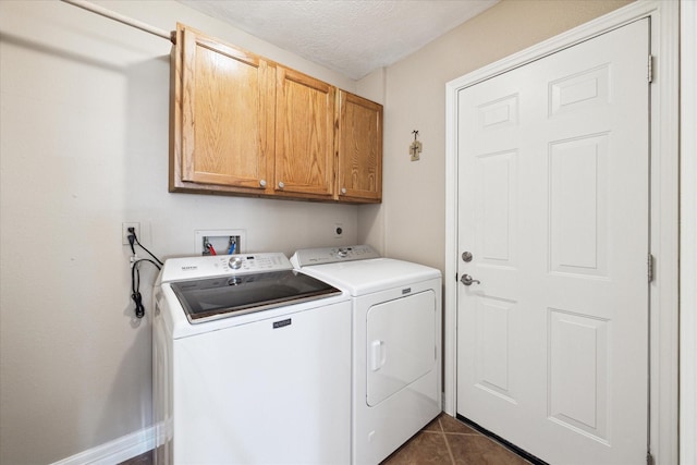 clothes washing area with washing machine and dryer, dark tile patterned floors, cabinets, and a textured ceiling