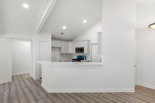 kitchen with white cabinets, lofted ceiling, kitchen peninsula, and stainless steel appliances