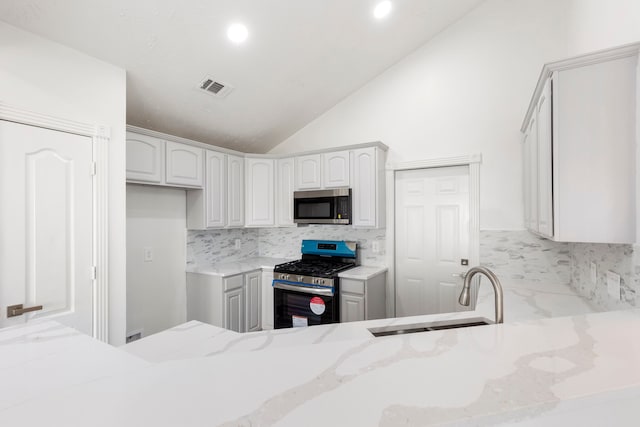 kitchen featuring light stone countertops, sink, stainless steel appliances, backsplash, and white cabinets