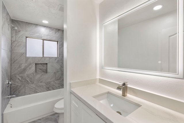 full bathroom featuring a textured ceiling, vanity, toilet, and tiled shower / bath