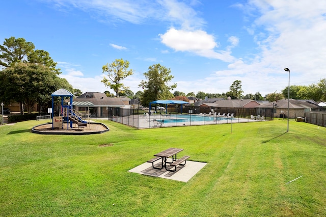 view of community featuring a playground, a lawn, and a swimming pool