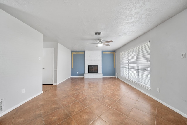 unfurnished living room featuring a fireplace, a textured ceiling, tile patterned floors, and ceiling fan