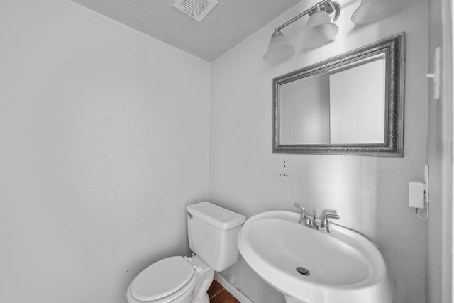 bathroom with tile patterned floors, a textured ceiling, toilet, and sink