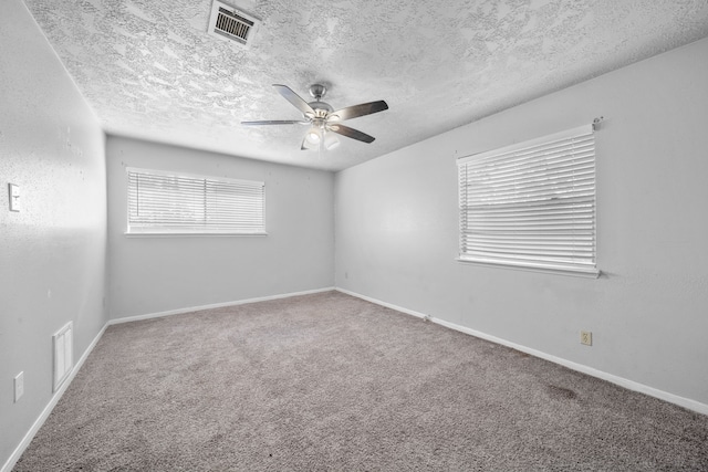 empty room featuring ceiling fan, carpet floors, and a textured ceiling