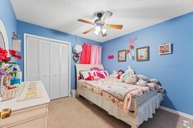 bedroom with a textured ceiling, light colored carpet, a closet, and ceiling fan